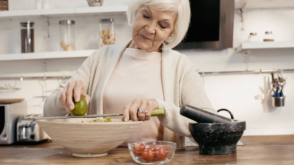 elderly woman grating lime to vegetable salad for thanksgiving dinner - Foto, afbeelding