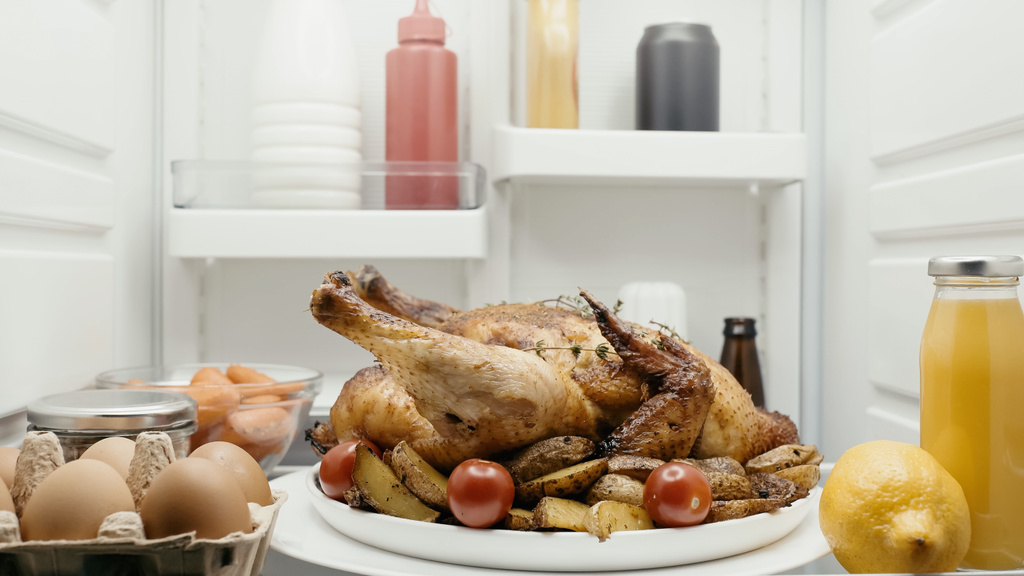 roasted turkey with potatoes and cherry tomatoes near orange juice, carrots and lemon and sauces in fridge - Fotografie, Obrázek