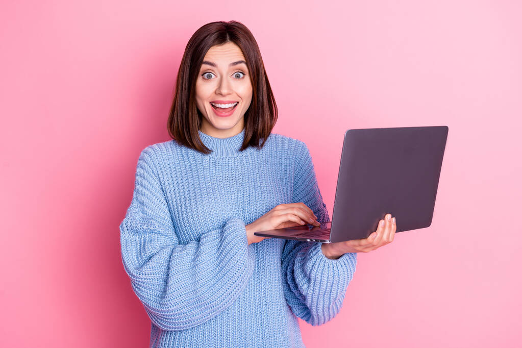 Πορτρέτο της ελκυστική χαρούμενη μεσίτης κορίτσι χρησιμοποιώντας φορητό υπολογιστή διασκεδάζοντας απομονωμένη πάνω από ροζ παστέλ χρώμα φόντο. - Φωτογραφία, εικόνα