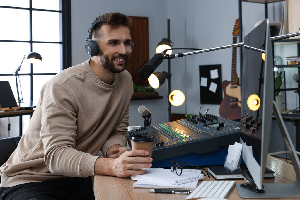 Człowiek z filiżanką kawy pracuje jako gospodarz radiowy w nowoczesnym studio - Zdjęcie, obraz