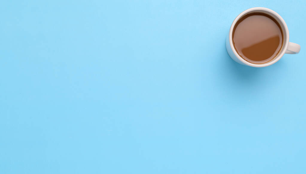 A top view of a cup of coffee on a blue background - copy space - Foto, Bild