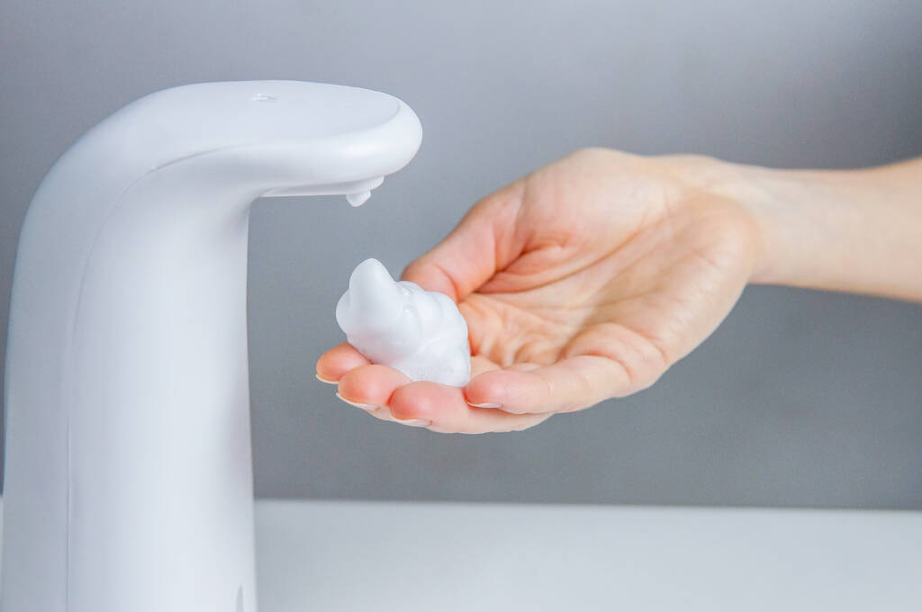 Limpeza das mãos com uma solução antisséptica automática sem contacto ou dispensador de sabão para prevenir pandemias e doenças - Foto, Imagem