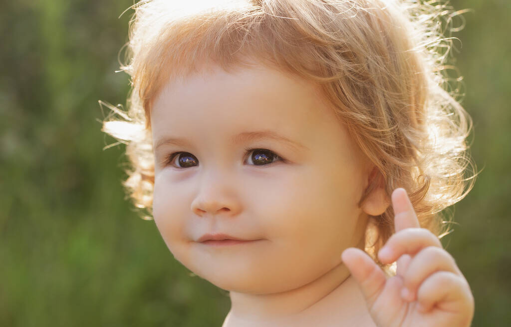 Primer plano retrato de un bebé lindo en el parque natural verde en el día soleado. Concepto de infancia y crianza. - Foto, imagen