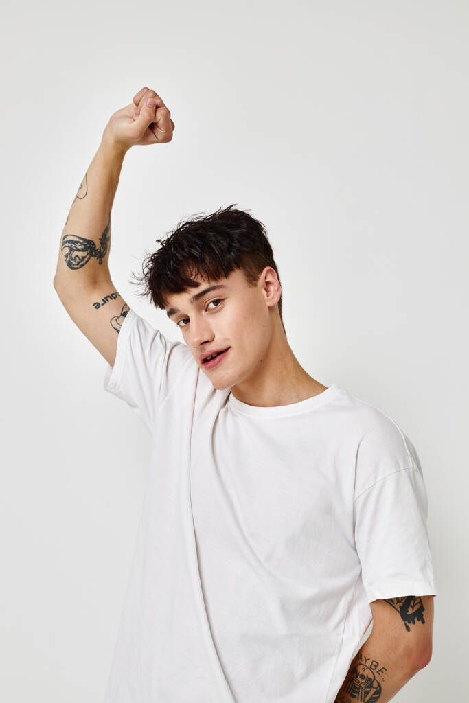 handsome guy tattoo on hands in white t-shirt light background unaltered - Photo, Image
