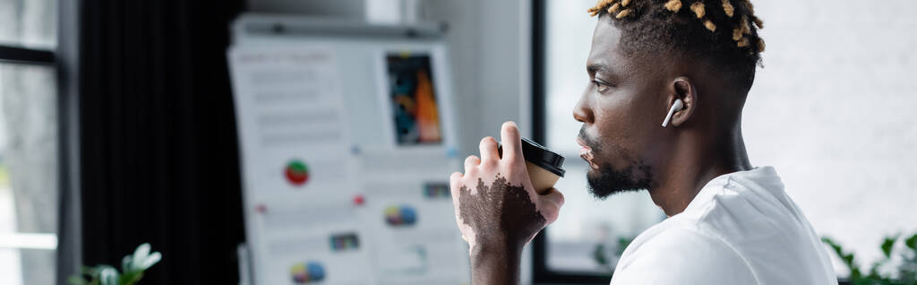 african american man with vitiligo skin and trendy hairstyle drinking coffee to go in office, banner - Foto, Imagem