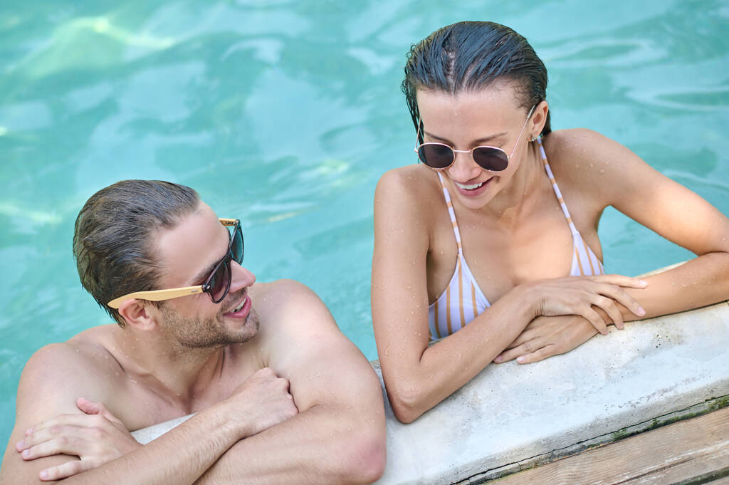 Ευτυχισμένος άντρας και γυναίκα περνούν χρόνο μαζί στην πισίνα. - Φωτογραφία, εικόνα
