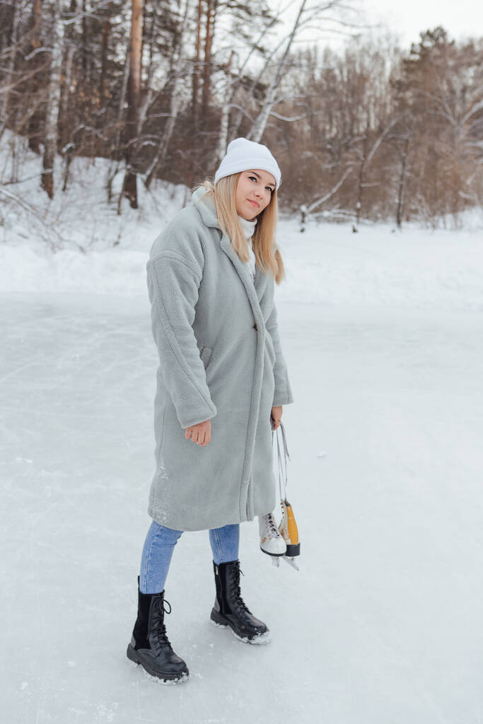 Belle jeune femme avec des patins à glace sur la patinoire. Fille va patiner sur la glace dans un hiver givré jour - Photo, image