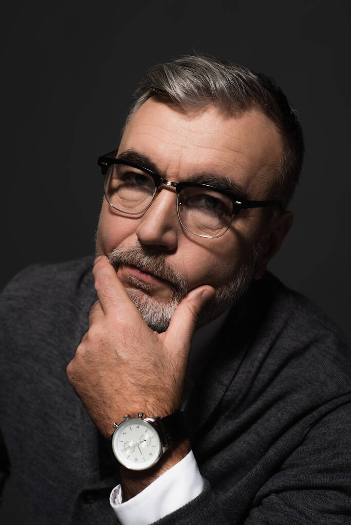 portrait of serious senior man in eyeglasses and wristwatch looking at camera isolated on dark grey - Fotografie, Obrázek