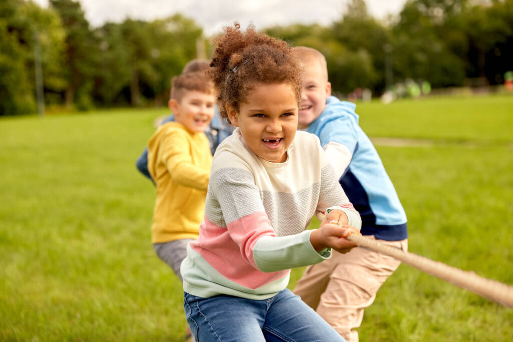 счастливые дети играют в перетягивание каната в парке - Фото, изображение