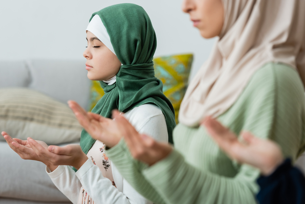 Προεφηβικό παιδί με χιτζάμπ προσεύχεται κοντά στους γονείς στο σπίτι  - Φωτογραφία, εικόνα