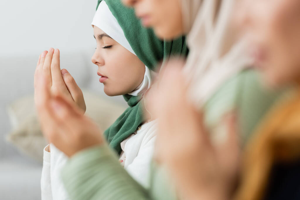 tiener meisje bidden in de buurt wazig vrouwen thuis  - Foto, afbeelding
