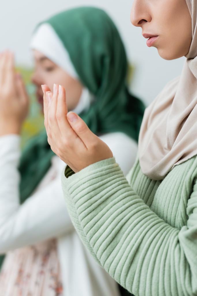 Молода мусульманка молиться біля розмитої дочки-підлітка вдома
  - Фото, зображення