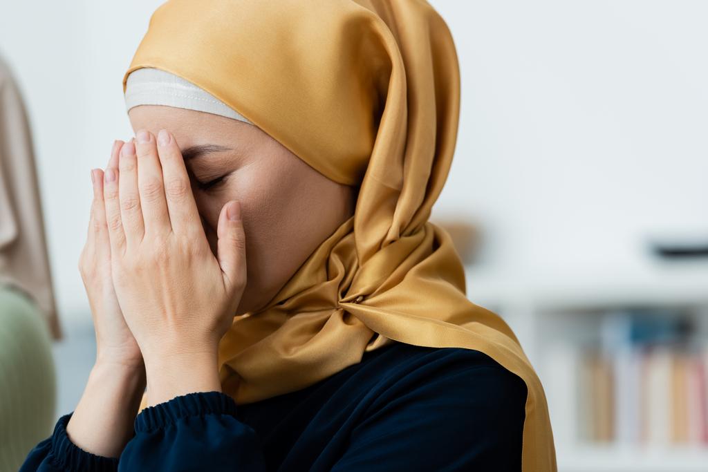 Азиатка в хиджабе покрывает лицо, молясь дома  - Фото, изображение