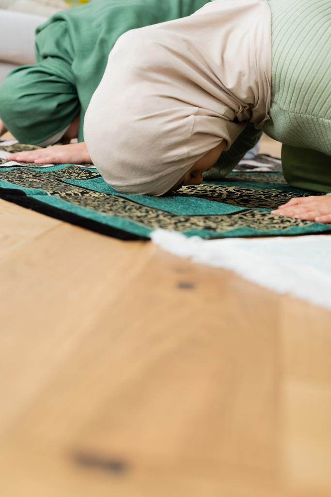 Arabo madre e figlia flessione mentre si prega su tappeti a casa  - Foto, immagini