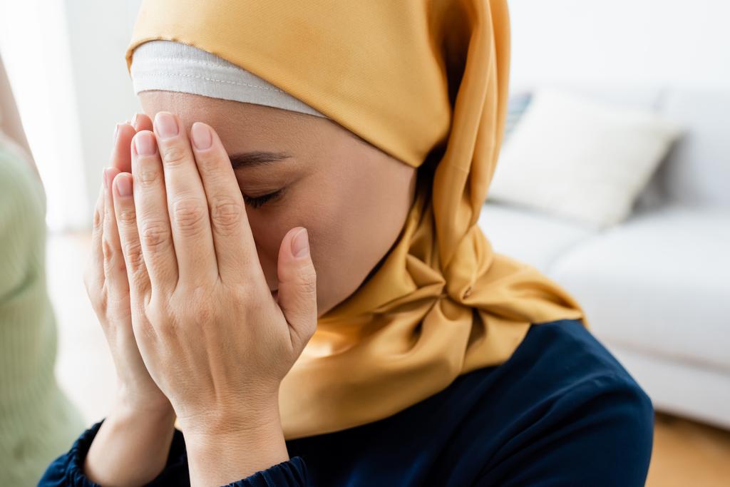 Ázsiai nő eltakarja arcát, miközben imádkozik otthon  - Fotó, kép