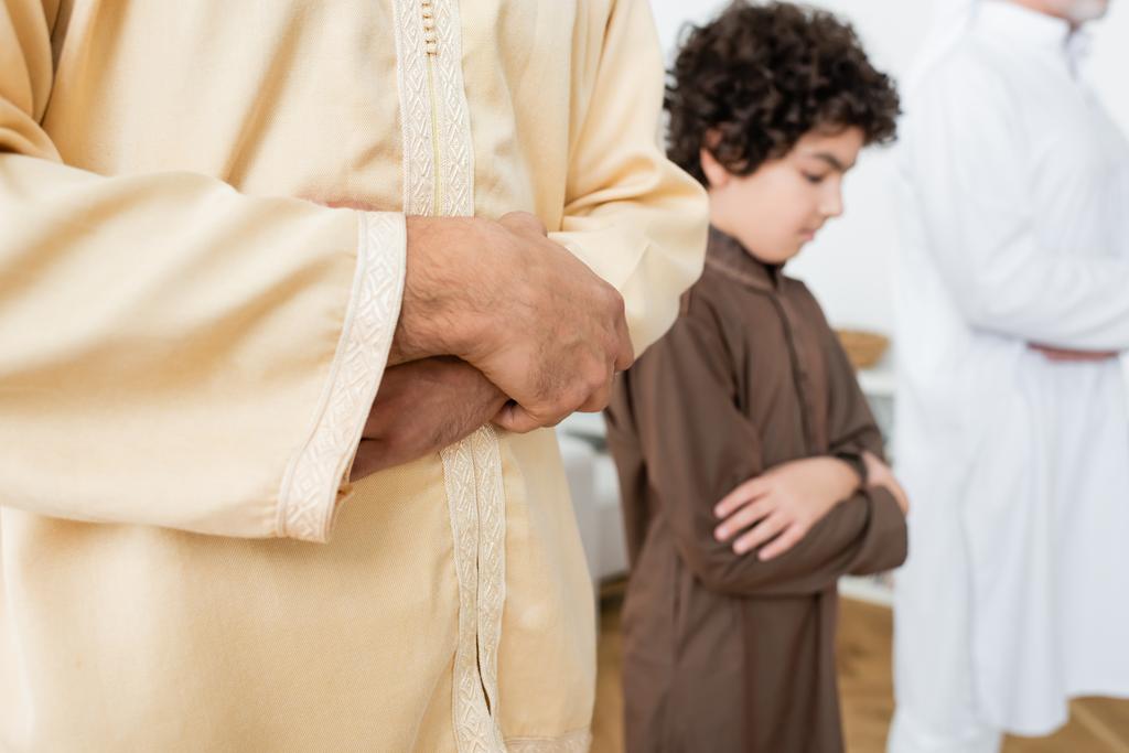 Giovane uomo musulmano che prega vicino al figlio offuscato a casa  - Foto, immagini