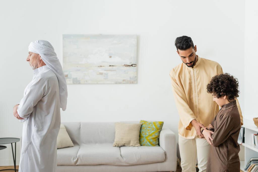 Dojrzały mężczyzna modli się w pobliżu muzułmańskiego ojca i syna w domu  - Zdjęcie, obraz