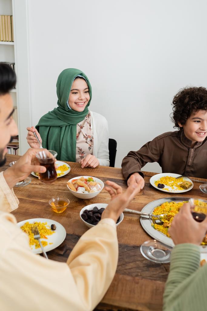onnellinen rotujenvälinen muslimi lapset syövät illallista hämärtynyt vanhempien kotona - Valokuva, kuva