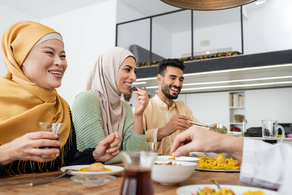 onnellinen arabialainen nainen syö päivämäärän hedelmiä illallisen aikana monikansallisen muslimiperheen kanssa - Valokuva, kuva