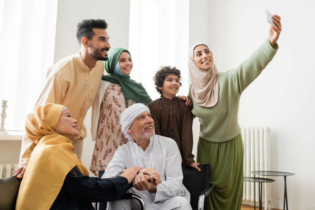 щаслива арабська жінка бере селфі на смартфон з мультикультурною мусульманською сім'єю
 - Фото, зображення