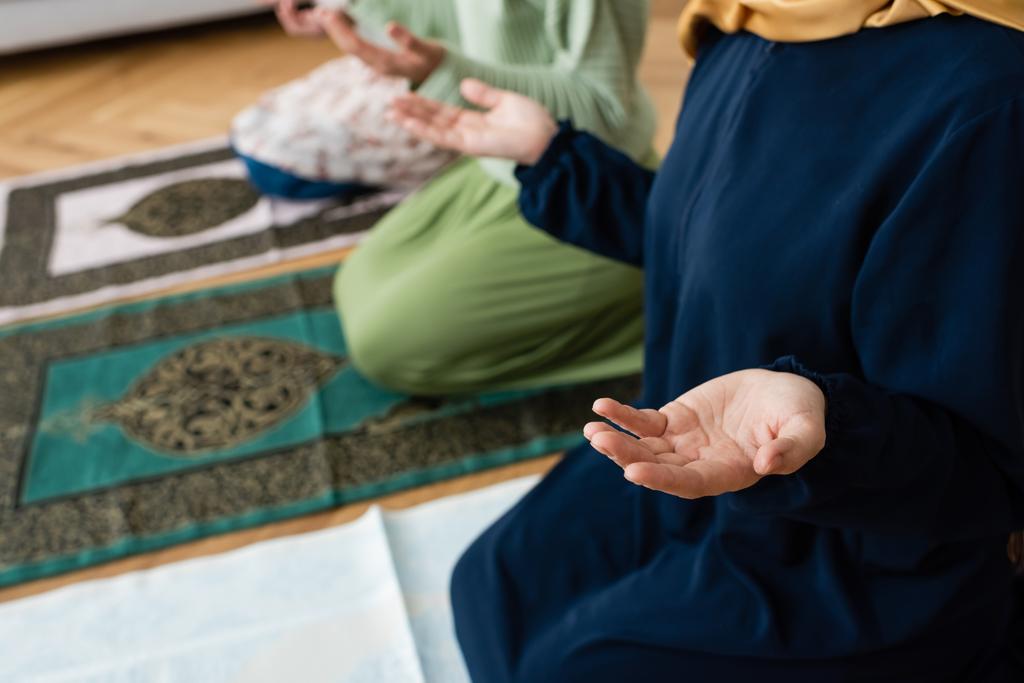 καλλιεργημένη άποψη των θολή μουσουλμάνων γυναικών με παραδοσιακά ρούχα προσεύχεται για χαλιά στο σπίτι - Φωτογραφία, εικόνα