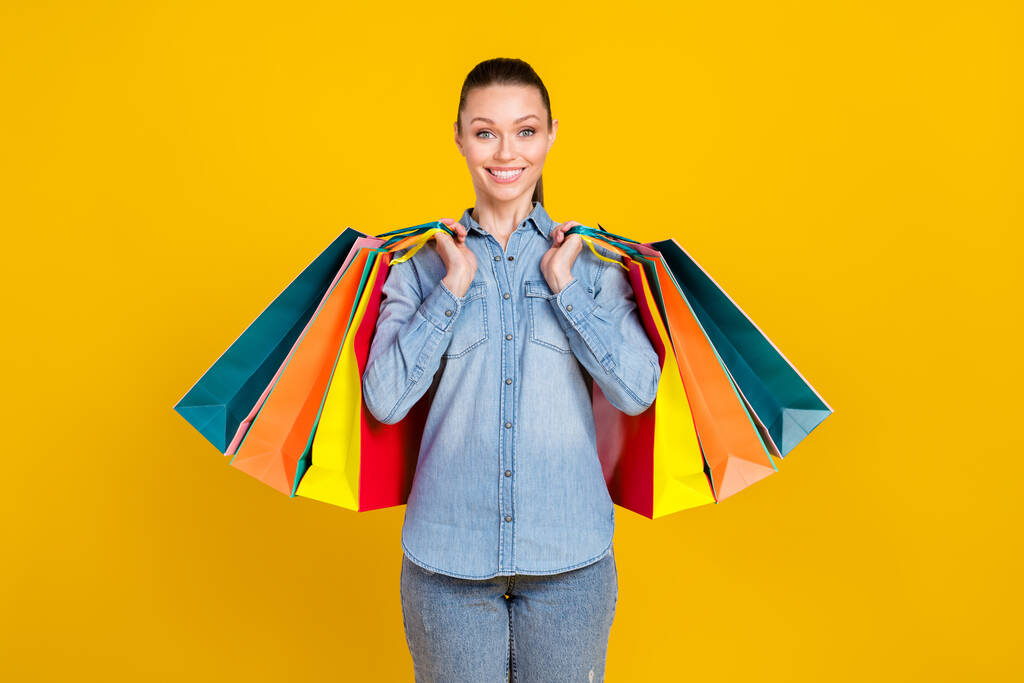 Photo portrait smiling girl keeping shopping bargains isolated vivid yellow color background - Fotoğraf, Görsel