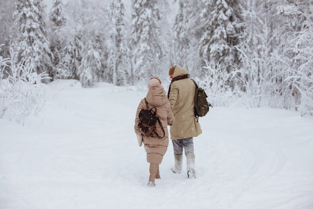 Coppia innamorata cammina attraverso la foresta invernale - Foto, immagini