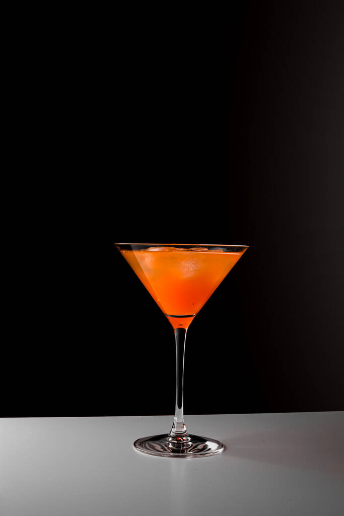 Fruit healthy cocktail from mango juice, orange peel spiral and ice on dark black background. - Fotó, kép
