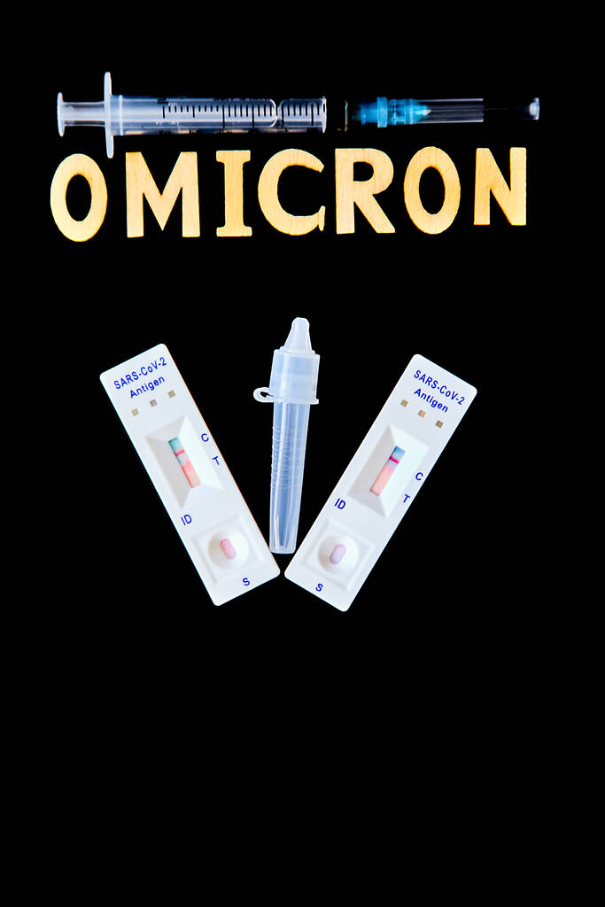 Omicron kelimesi ahşap harfler, şırınga, tıbbi enjeksiyon şişesi ve 2 covid-19 antijen testinden elde edildi. Siyah arka plan negatif. Konsept-mutasyona uğramış koronavirüs SARS-CoV-2 grip salgını. - Fotoğraf, Görsel