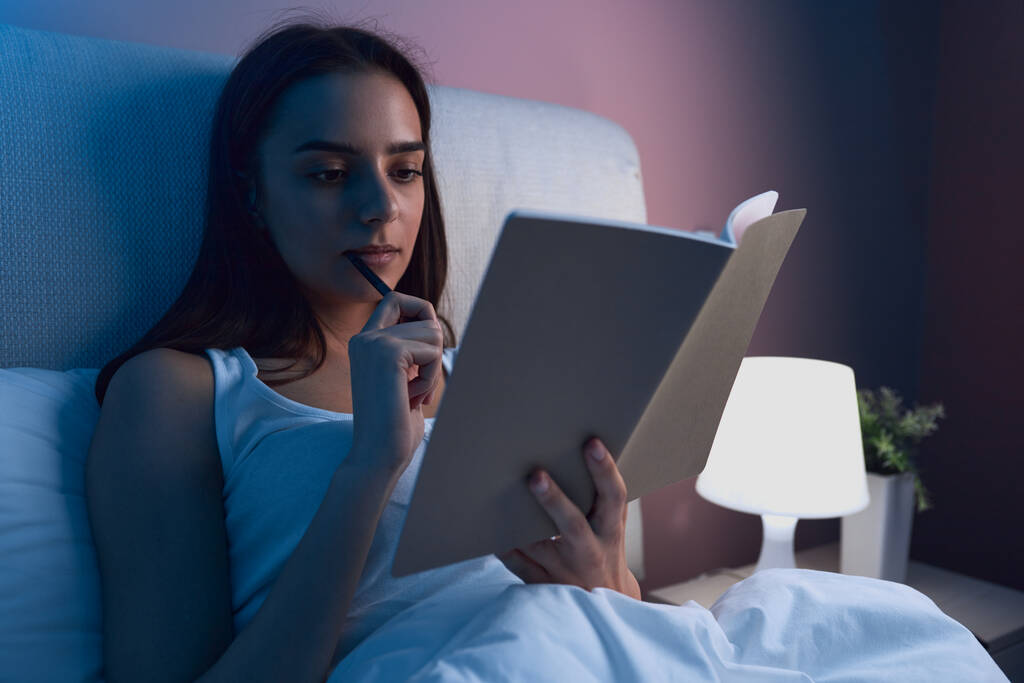 Woman writing in diary in bed - Photo, Image