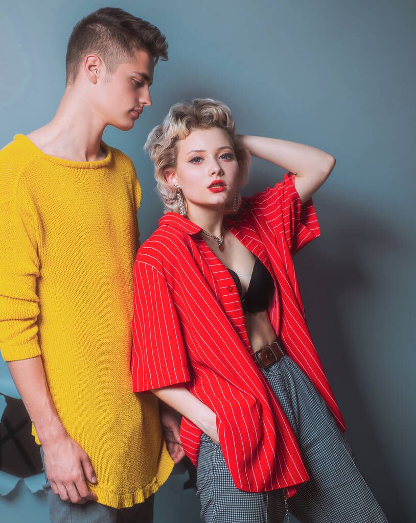 Prachtige vrouw met in rood shirt poseren met knappe brunette man in gele trui. Fashion portret mooi sexy paar. Commercieel ontwerp. Jongeren in jeans op een donkere achtergrond. Mode. - Foto, afbeelding