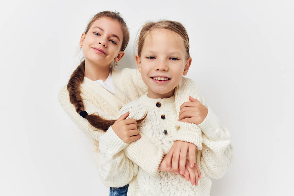 две маленькие девочки обнимают подругу на светлом фоне - Фото, изображение