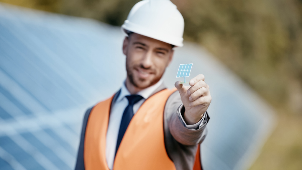 blurred and smiling businessman showing small solar battery model - Фото, изображение