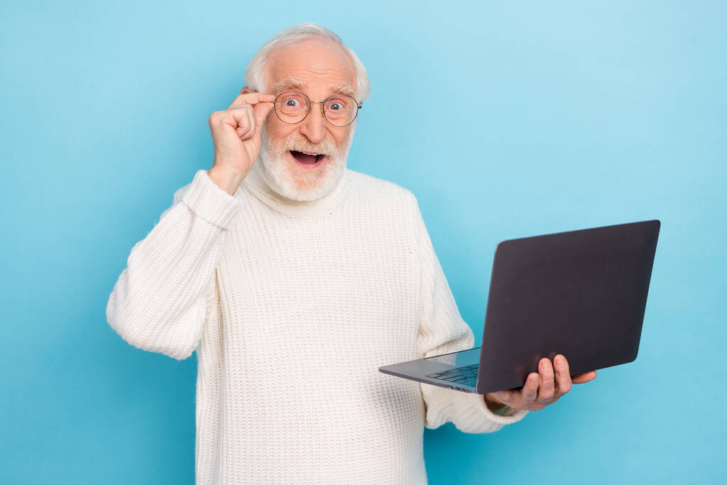 Etkileyici yaşlı sakallı adamın fotoğrafı dizüstü bilgisayara bak mavi arka planda izole edilmiş gözlük süveteri giy. - Fotoğraf, Görsel