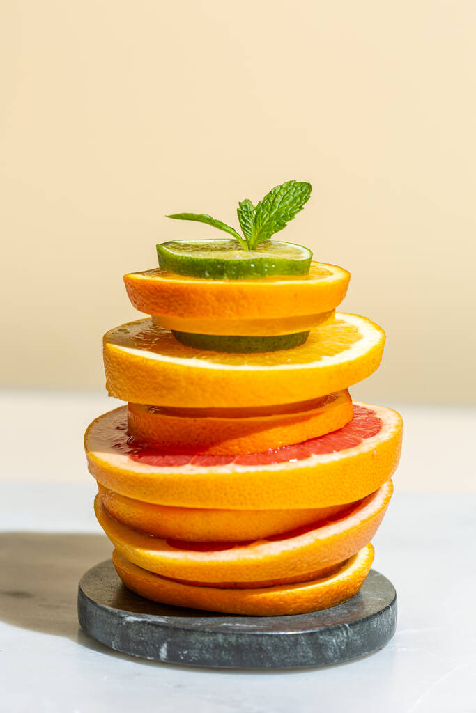 柑橘類のスライスは、石のスタンドに積み上げられ、ミントの葉、フルーツカクテル、新鮮なジュース - 写真・画像