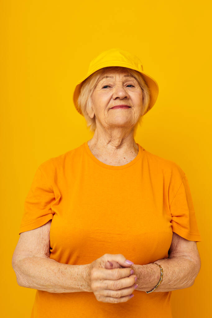 Retrato de uma velha mulher amigável estilo de vida feliz em uma cobertura para a cabeça amarela close-up emoções - Foto, Imagem
