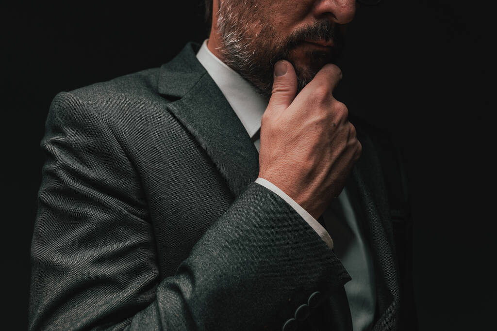 Overweging voor het starten van een bedrijf, elegante zakenman in grijs pak denken en plannen, low key portret met selectieve focus - Foto, afbeelding