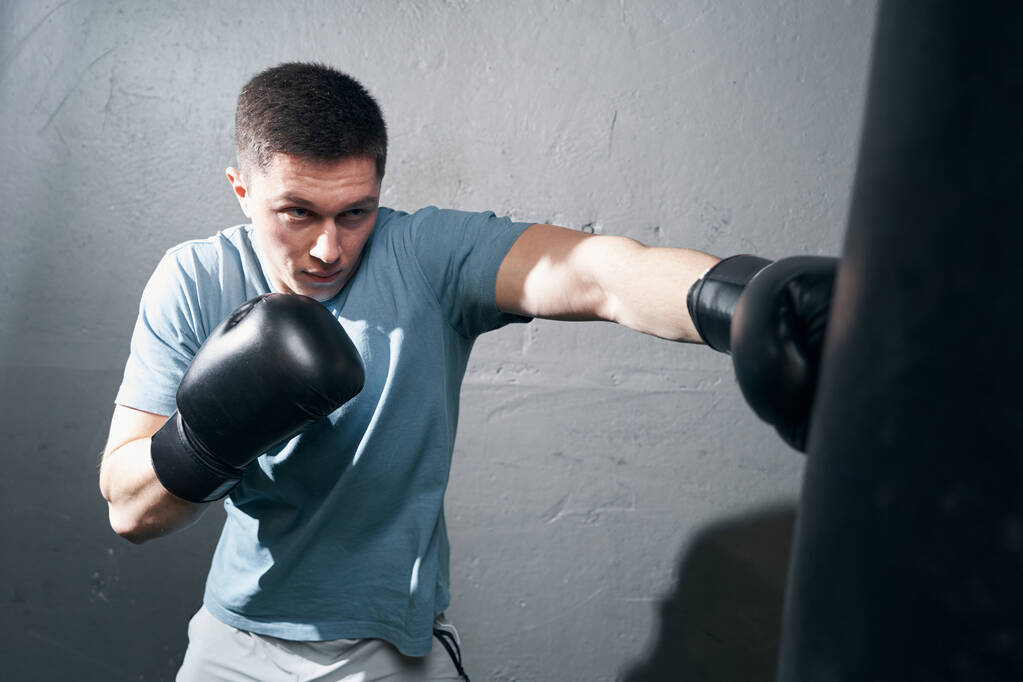 Enfocado joven caucásico boxeador masculino entrenamiento en interiores - Foto, imagen