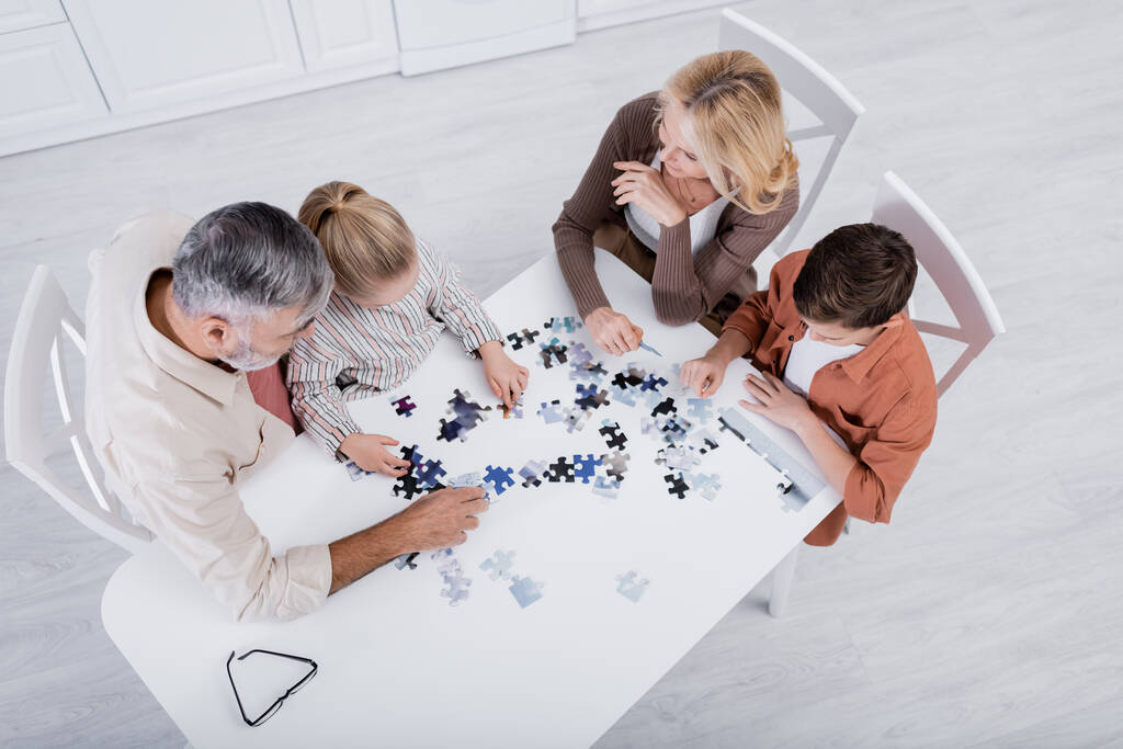 vista aerea dei bambini con i nonni che giocano puzzle game sul tavolo della cucina - Foto, immagini