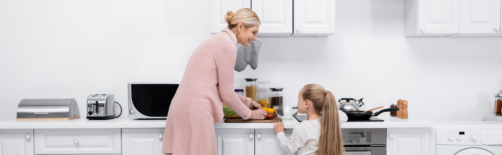 mujer madura con su nieta cocinando en la cocina, pancarta - Foto, Imagen
