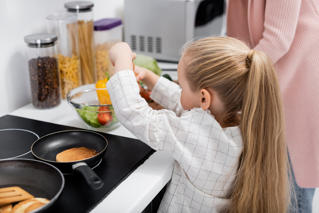 bambina che prepara insalata di verdure fresche con nonna in cucina - Foto, immagini