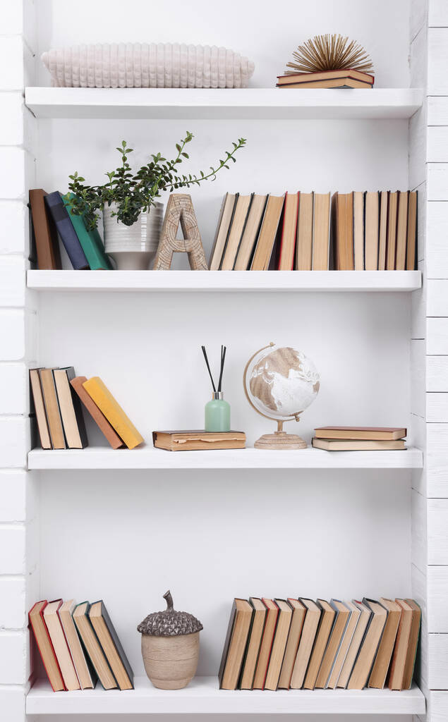 Collection of books and decor elements on shelves indoors - Photo, Image