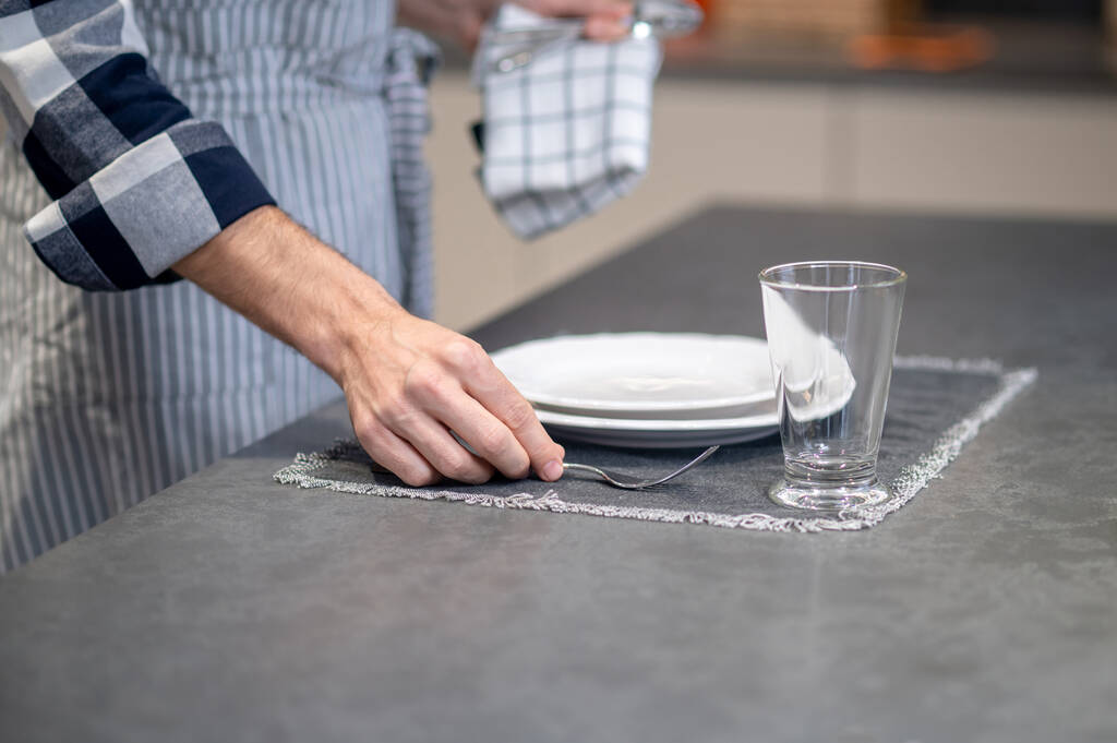 Mannelijke hand zetten vork op servet in de buurt plaat - Foto, afbeelding