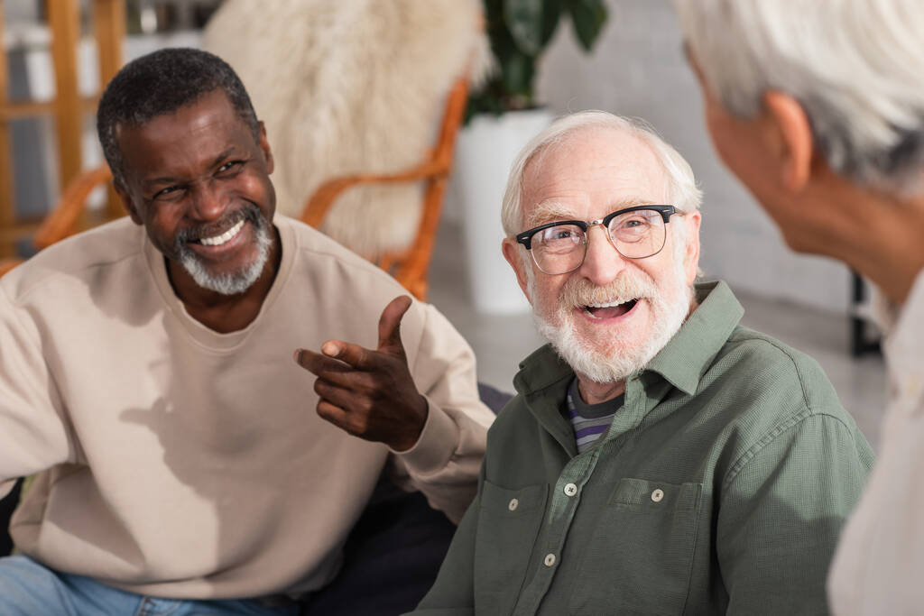 Idős férfi nevet közelében multietnikus barátok otthon  - Fotó, kép