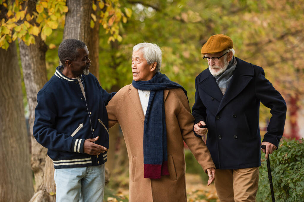 Asian man talking to elderly multiethnic friends on urban street  - Photo, Image