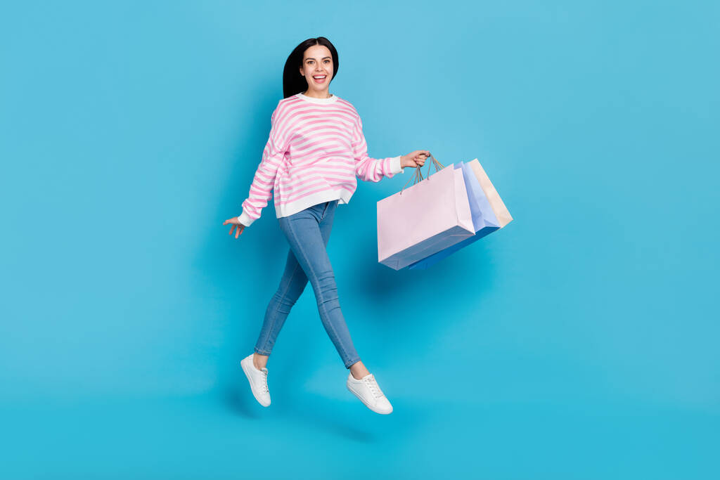 pleine taille photo de jeune femme sauter en haut magasin centre commercial discount cadeau isolé sur fond de couleur bleue - Photo, image