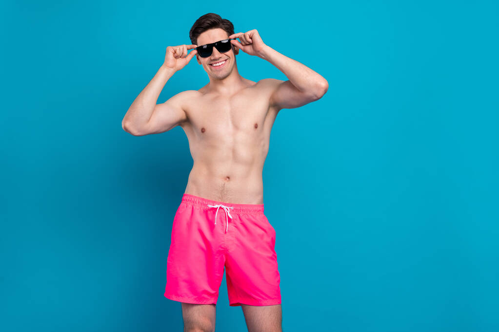 Foto de joven guapo hombre feliz sonrisa positiva usar gafas de sol hipster fresco aislado sobre fondo de color azul - Foto, imagen