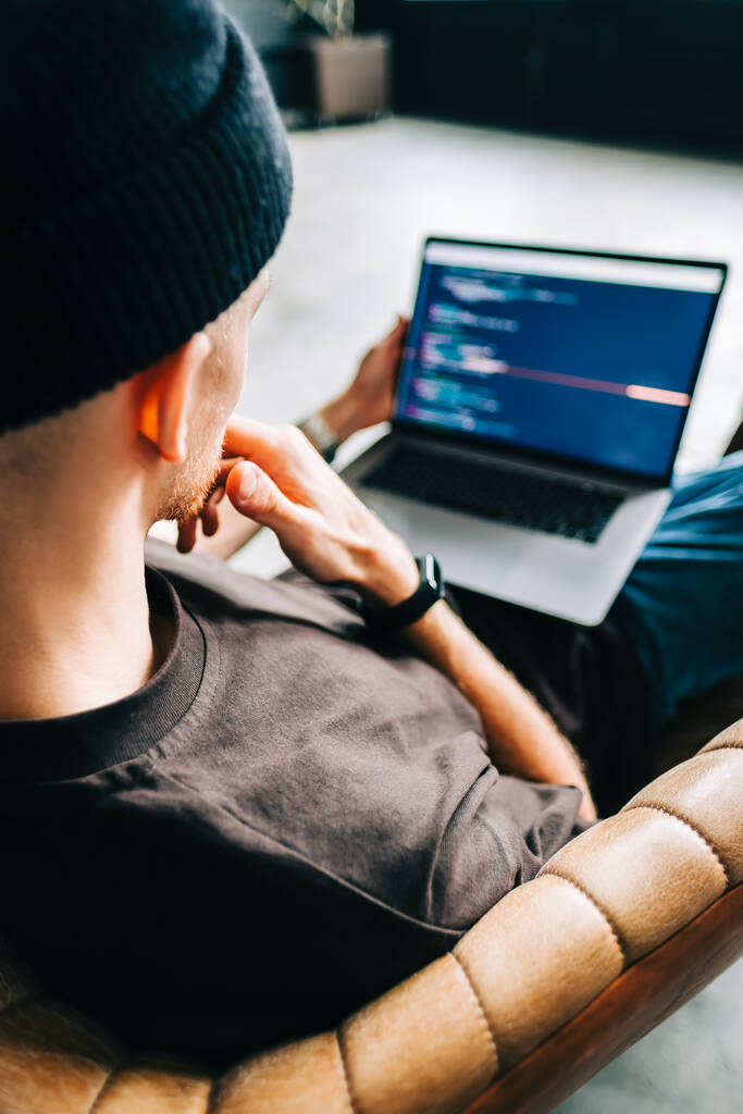 Jeune homme développeur mobile écrit le code du programme sur un ordinateur, le travail de programmeur dans le bureau à domicile. - Photo, image