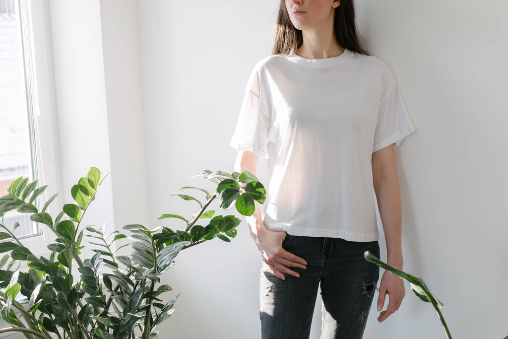 Γυναίκα φορώντας λευκό κενό t-shirt με χώρο για το λογότυπό σας, mock up ή σχεδιασμό σε εσωτερικούς χώρους - Φωτογραφία, εικόνα