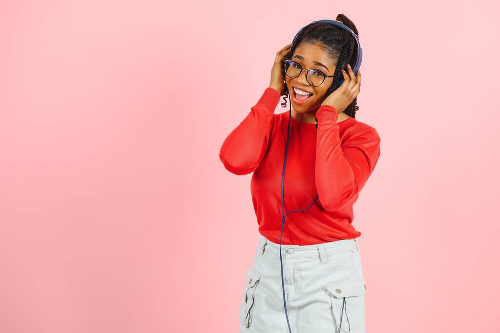 chica afroamericana en auriculares sobre un fondo rosa - Foto, imagen